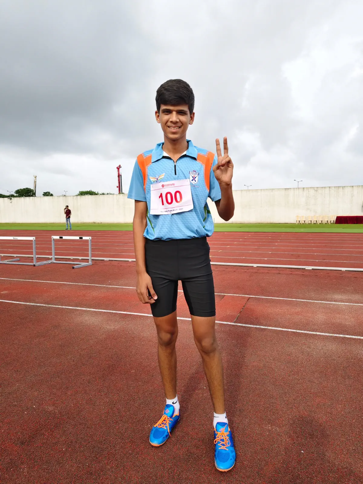 Athlete on synthetic track posing with peace sign