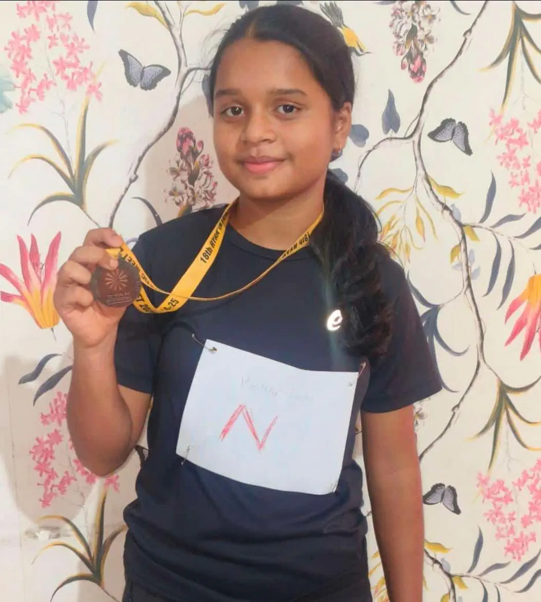 Young Risers girl athlete holding up her medal with pride