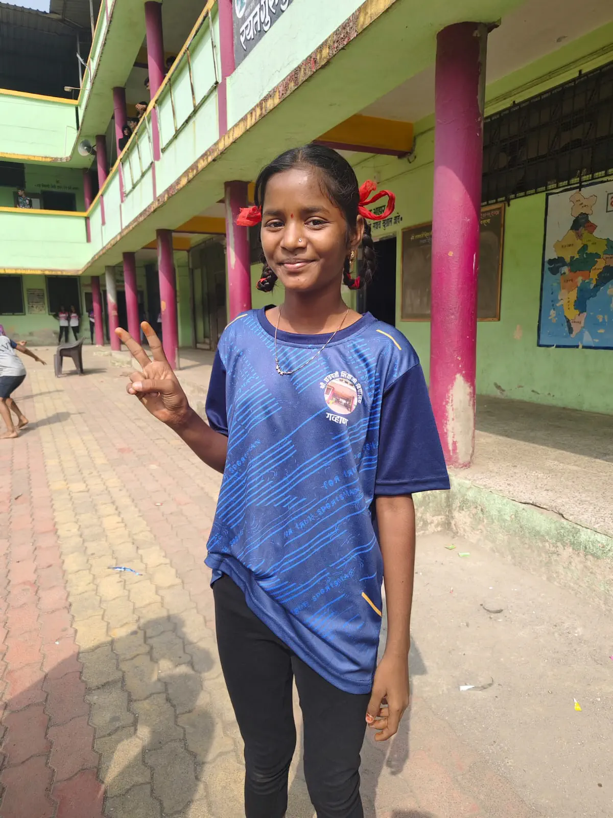 Schoolgirl in blue sports jersey posing in front of campus building