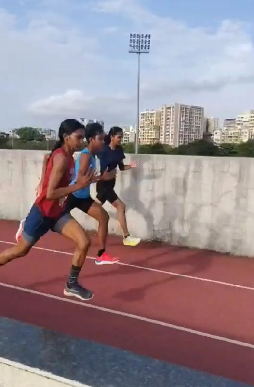 Three female athletes sprinting down the home straight